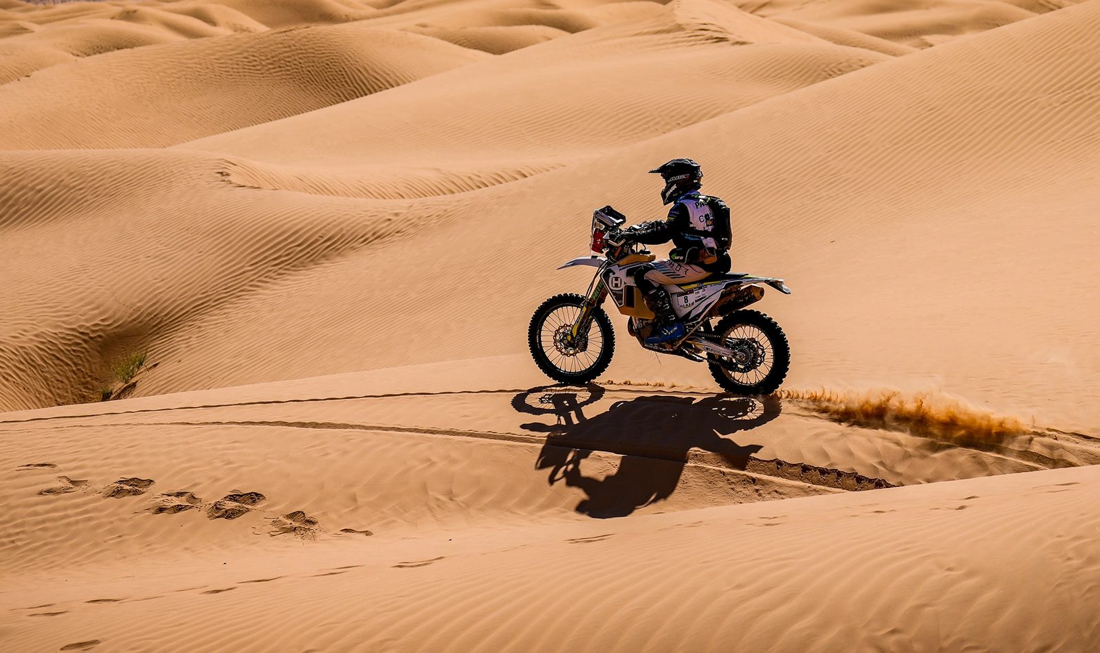 Rider cresting a dune under open sky during Fenix Rally in Tunisia