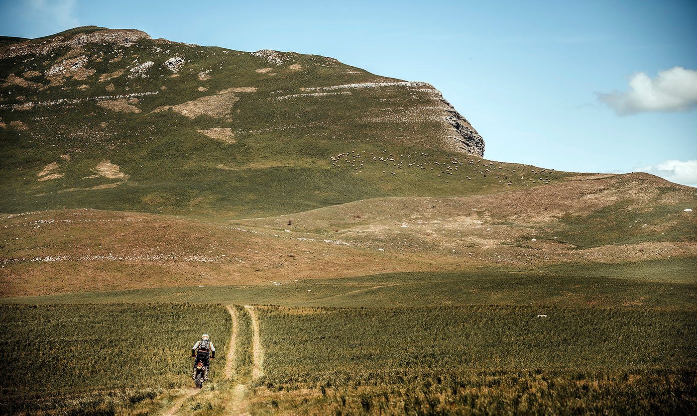 Rider on a narrow track crossing green highland terrain during Illyria Raid