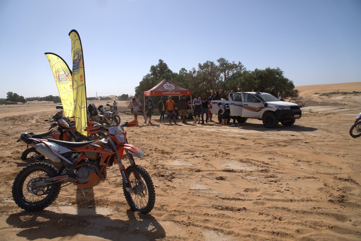 Rally motorcycle parked at a desert bivouac with support vehicles during Morocc'n Roll