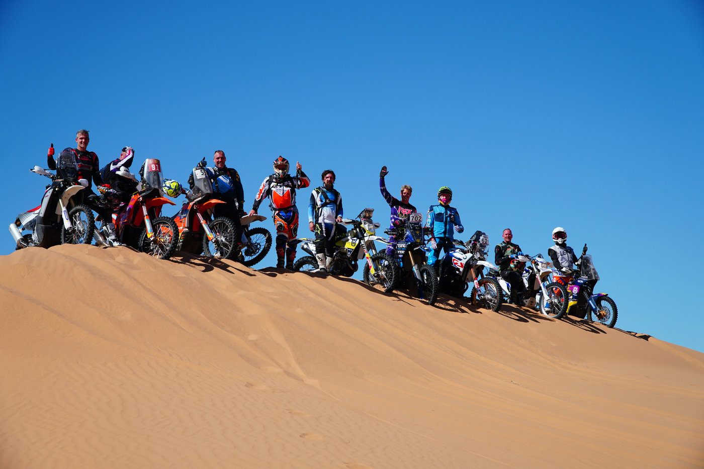 Group of riders lined up along a sand ridge during Wiedemann Experience roadbook training in Morocco